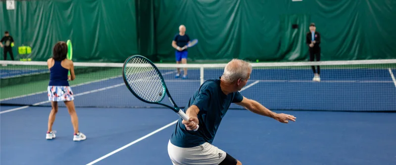 Adults and a junior player on an indoor tennis court
