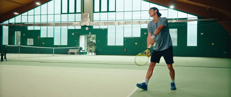 A player returning a shot on an indoor tennis court