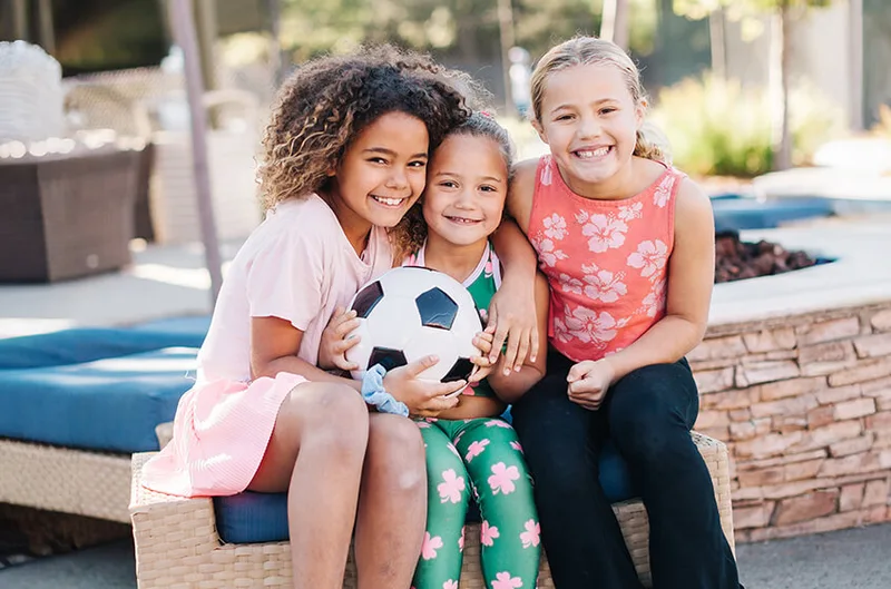 Three girls with a soccer ball at a Bay Club camp